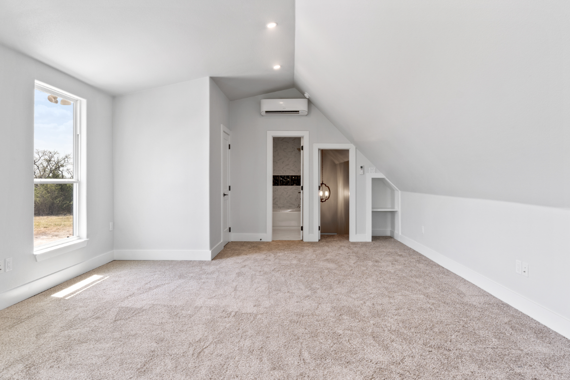 Newly installed neutral carpet in a bright, empty upstairs room with white walls, a sloped ceiling, and natural light.
